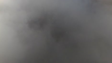 aerial tilting shot revealing a mountain valley covered with clouds in iceland