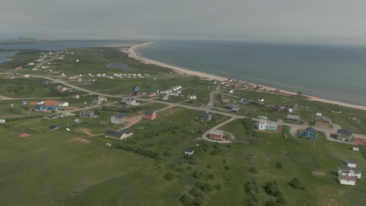 Aerial tilt reveal view of coastline village on green Magdalen Islands
