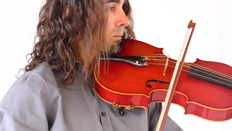 close up shot of hispanic man in grey shirt with long hair and goatee plays red viola with bow in slow motion against white back drop