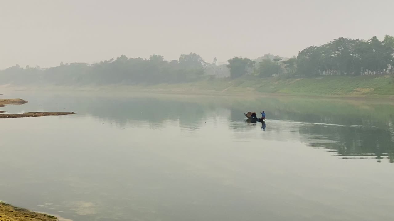 los pescadores reman en un bote pequeño en un río asiático brumoso, rodeados de serena belleza natural