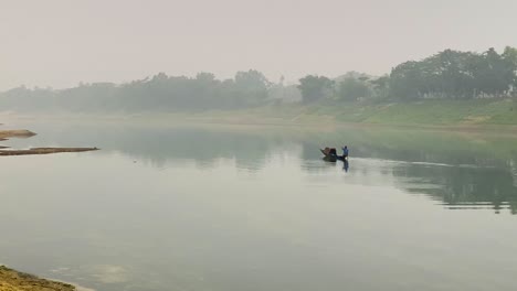 fishermen paddle a small boat on a foggy asian river, surrounded by serene natural beauty