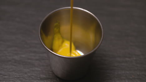 pouring mustard into a stainless steel ramekin for dipping