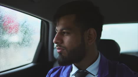 man looking out car window on a rainy day