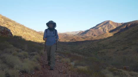 excursionista camina hacia la cámara en un árido paisaje montañoso, australia central