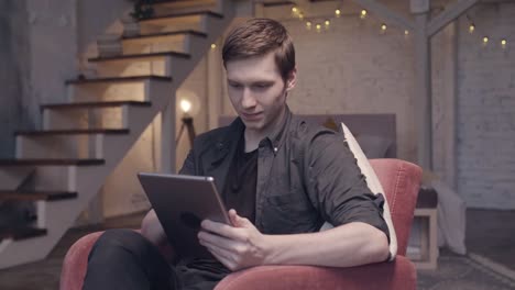 young man using tablet in a cozy home setting