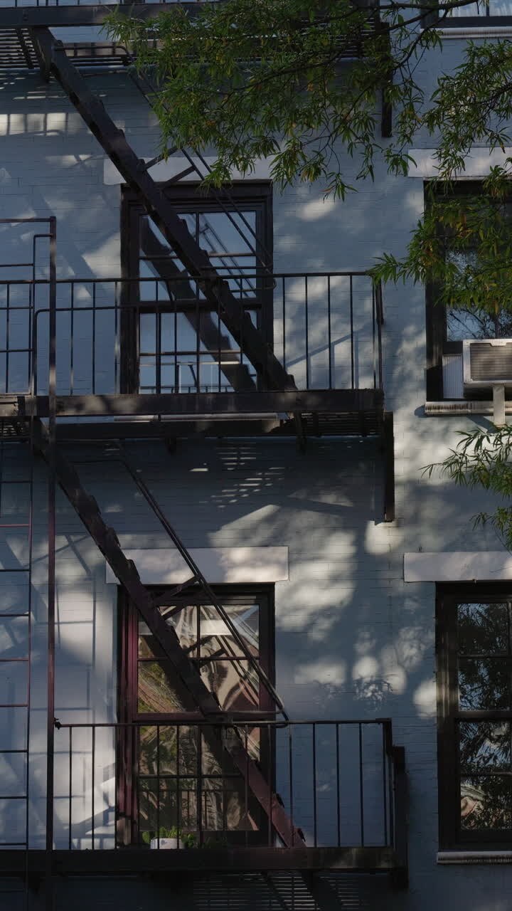 Luce solare e ombre di alberi in movimento su una facciata di un edificio urbano.