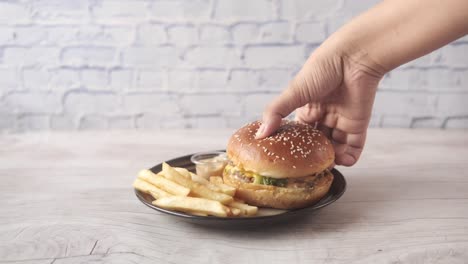 hand holding a delicious burger with fries