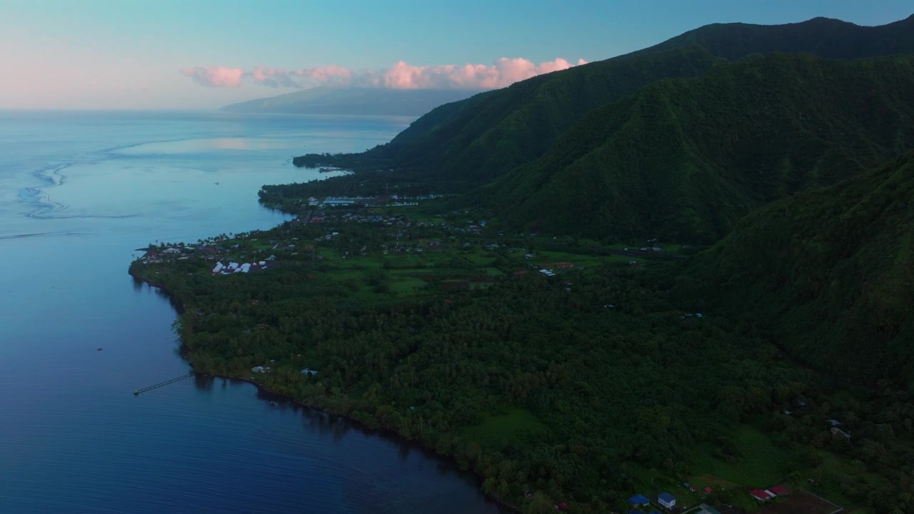 Early morning sunrise Town of Teahupo'o village End of the Road Tahiti French Polynesia aerial drone view shaded neighborhood buildings Teahupo'o lagoon surfing Passe Havea coral reef forward pan