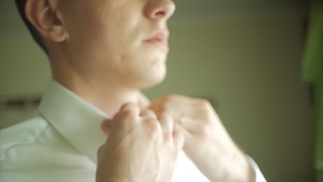 man buttoning his white shirt