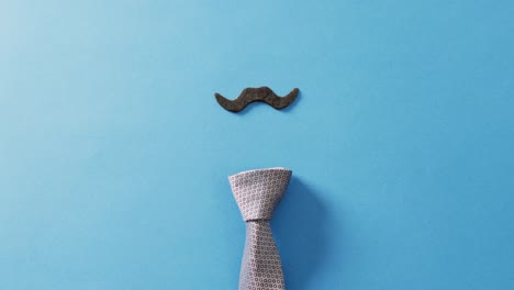 Video-of-false-moustache-and-tie-on-blue-background-with-copy-space