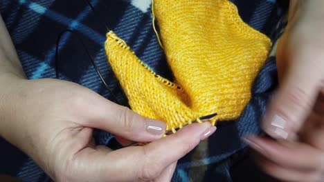 women's hands knit woolen jacket with knitting needles. top view, close-up of hands and knitting.