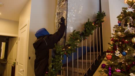 shot from bottom of staircase; delivery workers push plastic-wrapped mattress up stairs