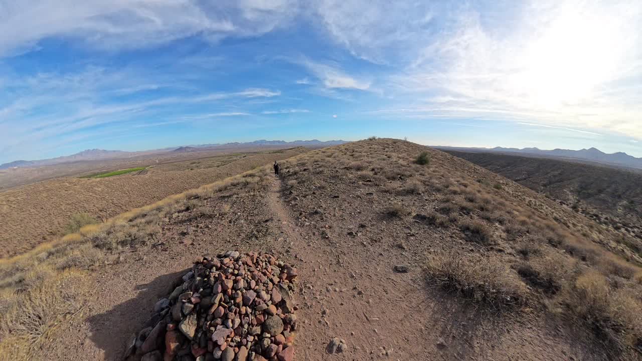 Senior woman walks up hill towards a rock pile.