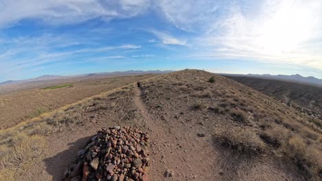 senior woman walks up hill towards a rock pile.