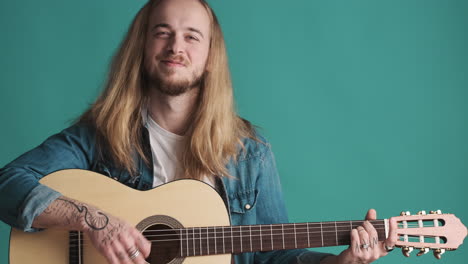 caucasian young man playing guitar on camera.