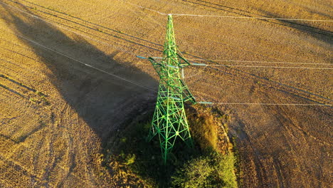high voltage electricity tower in rural field, power supply to countryside village, drone view