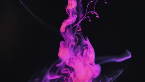 slow motion video of purple watercolor ink mixing in water against black background