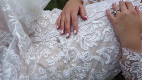 close up of wedding dress while bride is laying on grass