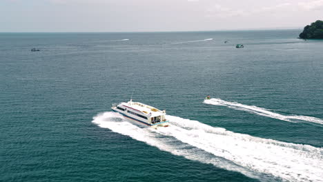 tourist speedboat and jetski travelling in ocean, aerial tracking view.