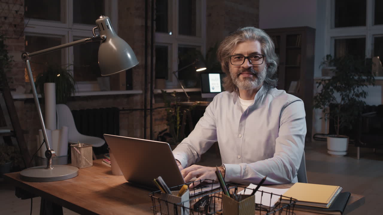 Mature man working on laptop at a desk in a stylish office