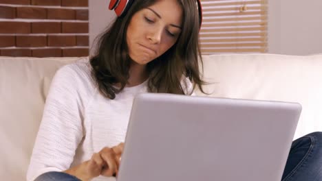 mujer preocupada usando computadora portátil en el sofá