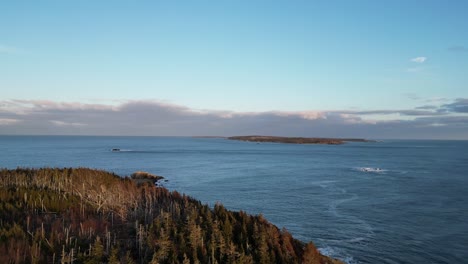 A-fly-over-of-Mira-Bay-from-Scatarie-Island,-Flying-towards-a-small-town-over-looking-the-ocean