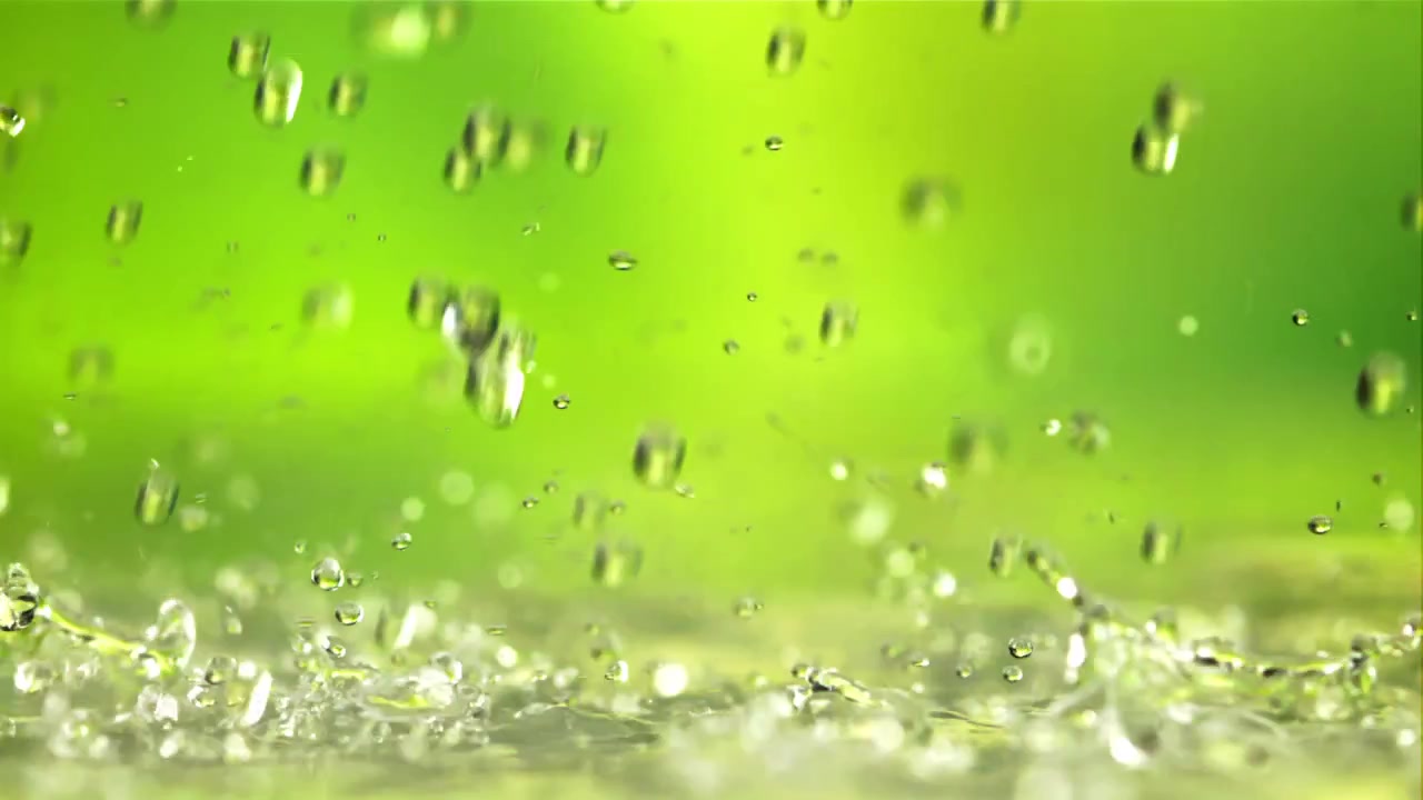 Rinfrescanti goccioline d'acqua che cadono e schizzano su uno sfondo verde