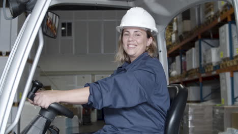 heureuse travailleuse caucasienne assise dans un forkfit et regardant la caméra