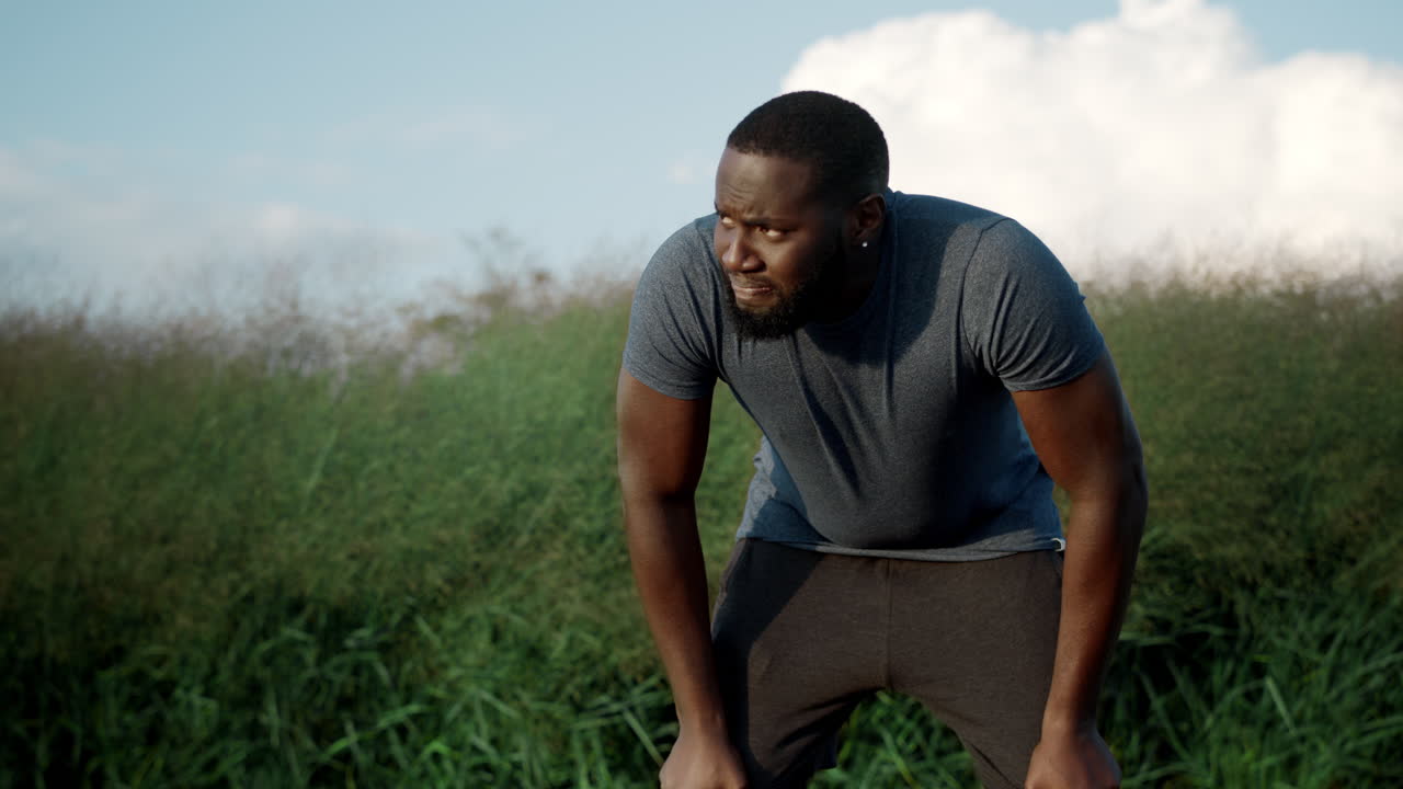 Athlete taking break after run in park. Guy breathing after training outdoors