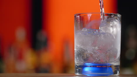 pouring soda water with ice into a glass