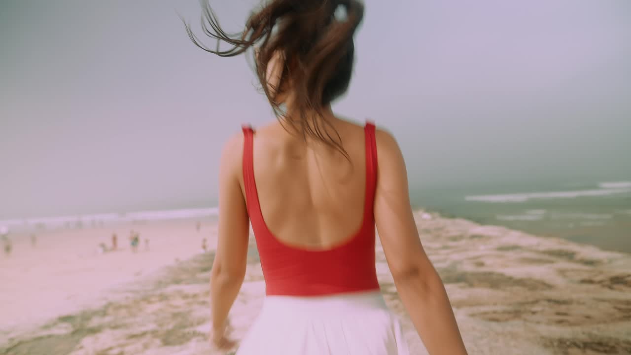 Young Woman Running on a Pier Towards the Ocean