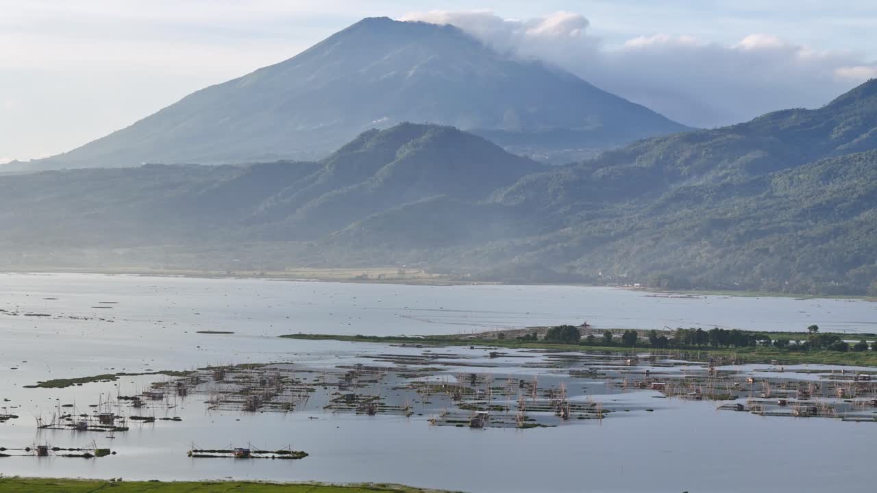 montaña volcánica y lago con balsas de pesca