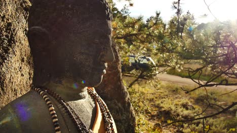 Lens-flare-across-a-stone-Buddha's-face-at-the-stupa-in-Red-Feather-Lakes,-CO