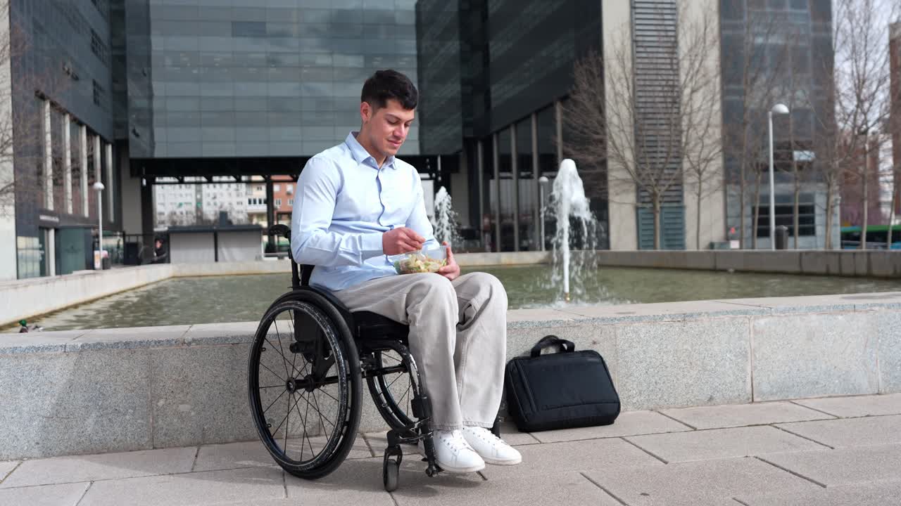 Young Man in Wheelchair Eating Salad Outdoors in Business District