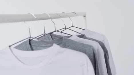 Video-Von-Weißen-Und-Grauen-T-Shirts-Auf-Kleiderbügeln-Und-Kopierraum-Auf-Weißem-Hintergrund
