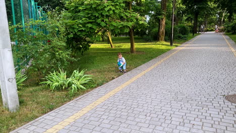 baby boy goes to pick up the ball from the grass. kid brings his ball to the camera. toddler playing in the park.