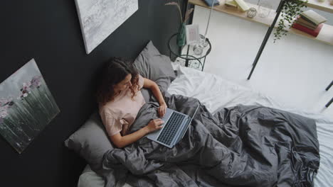 woman working on laptop in bed