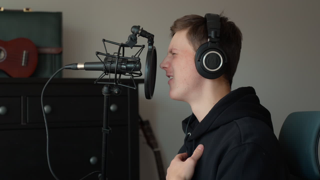 Young man recording music in home studio, focused and passionate