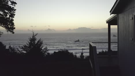 Side-part-of-wooden-house-overlooking-ocean-at-sunset