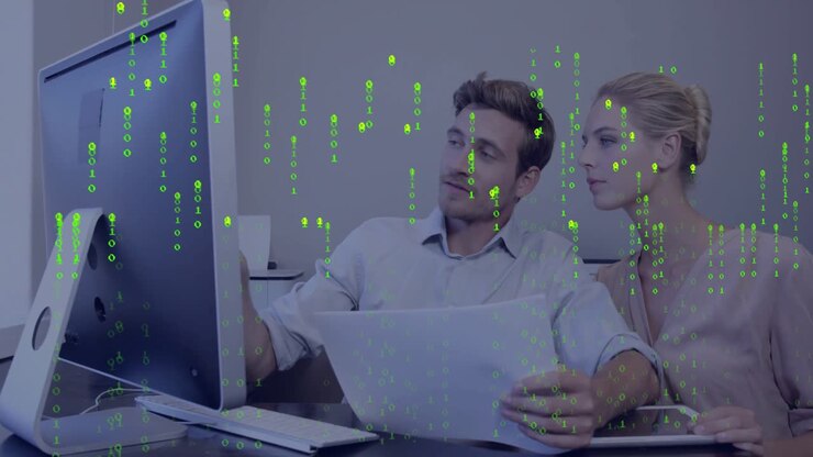 Kolleger trykker på rapport mens de analyserer data med et binærkode-overlegg som vises på et kontor.