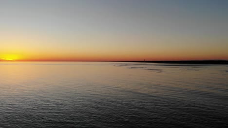 Cinematic-aerial-drone-flying-over-ocean-at-the-last-glimpse-of-a-beautiful-sunset