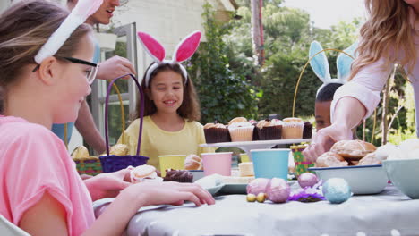 parents with children wearing bunny ears enjoying outdoor easter party in garden at home