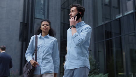 handsome man speaking cellphone at glass office building. modern corporate area