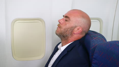 close up of a nervous man with a beard taking deep breaths trying not to panic with anxiety on a passenger plane airliner airplane