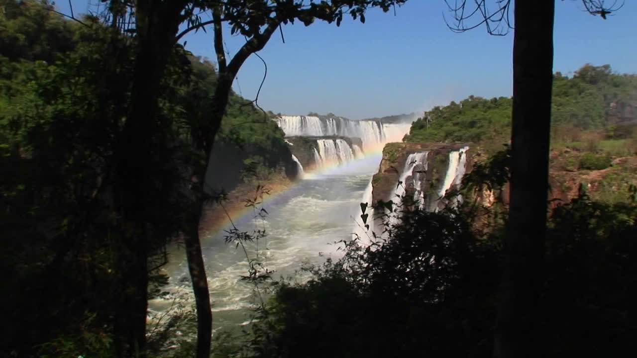 un zoom en las cataratas del iguazú con un arco iris en primer plano