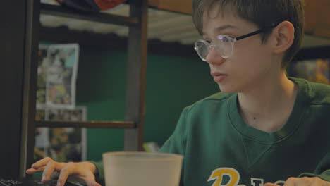 an attractive young boy works diligently on his homework at his desk in his bedroom