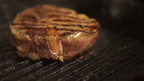 tongs turning over steak cooking on a bbq pan - close up detail