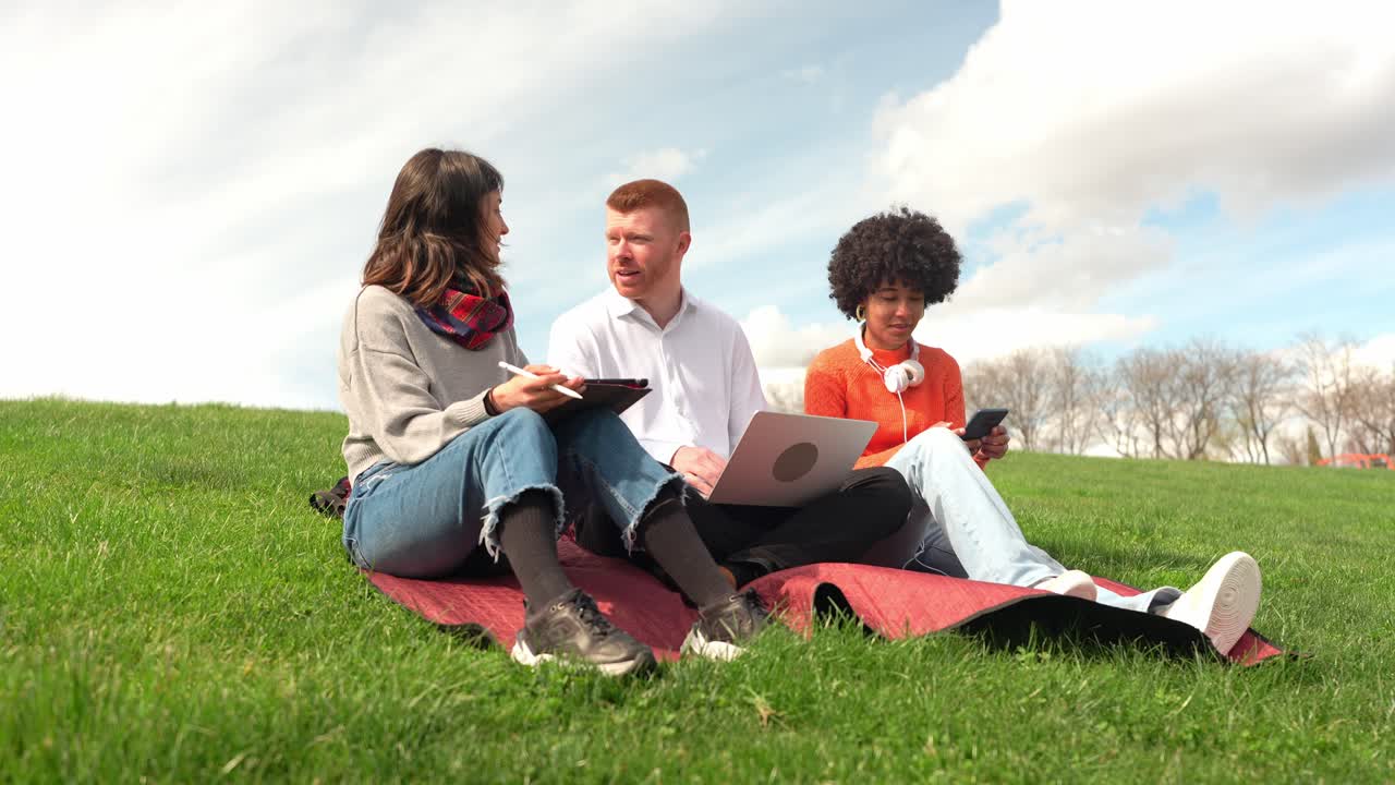 Group of students working on laptop outdoors