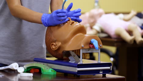 medic shows how to insert oxygen tube in nose of a medical dummy. competent doctor with nesessary instruments in hands.