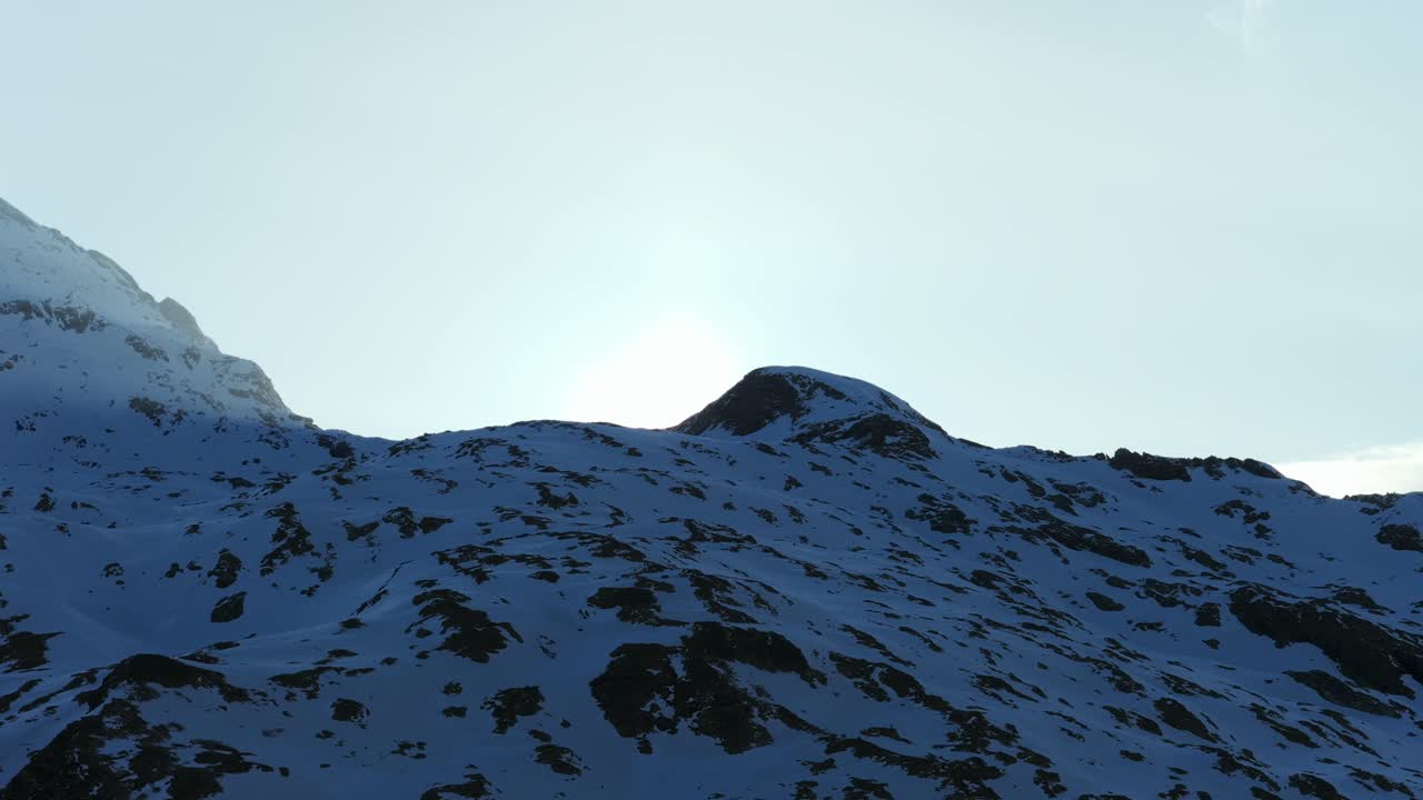 Majestic snow-covered mountains, bright sun creates lens flare over pristine alpine landscape, Italy. Aerial drone, copy space